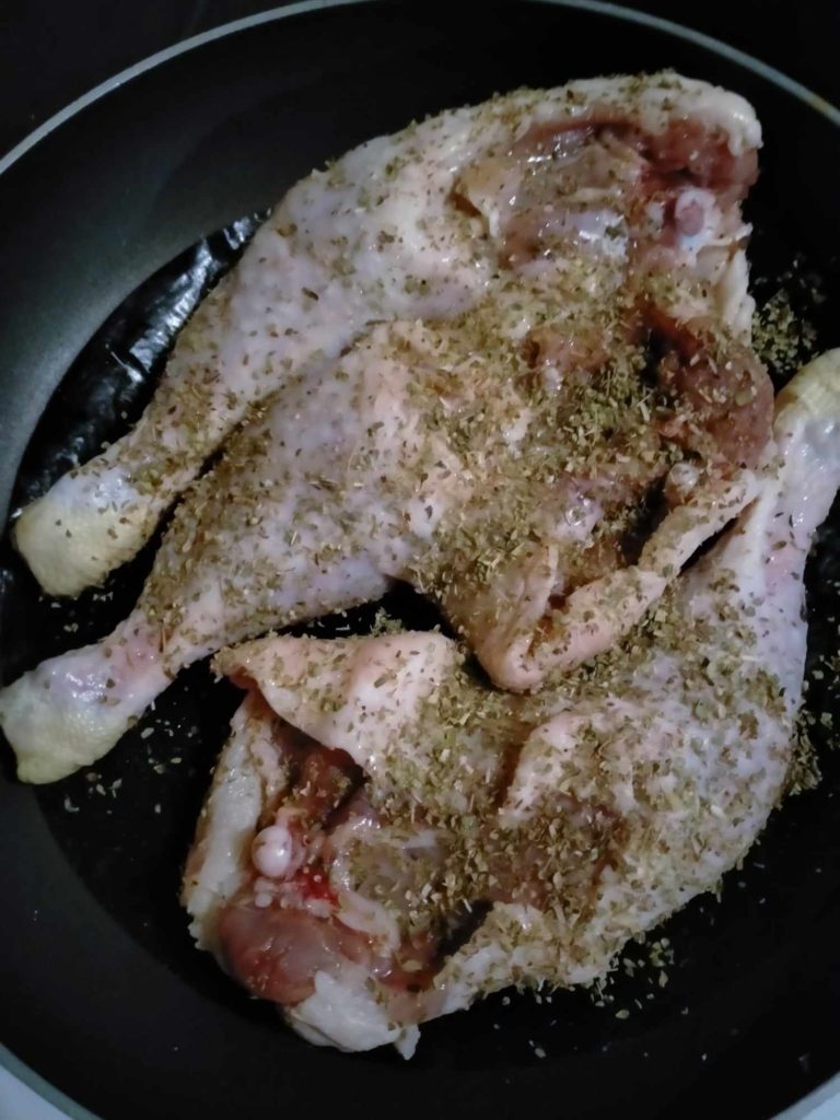 poulet cru dans une casserole, on l'a assaisoné puis placé sur un film cuisson